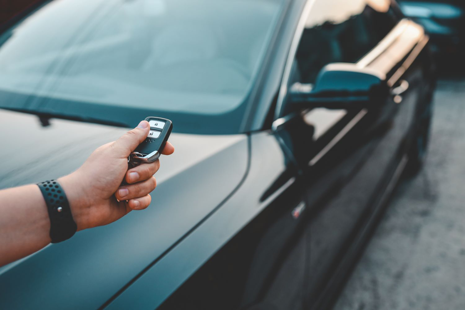 person holding transponder key pointing to his car